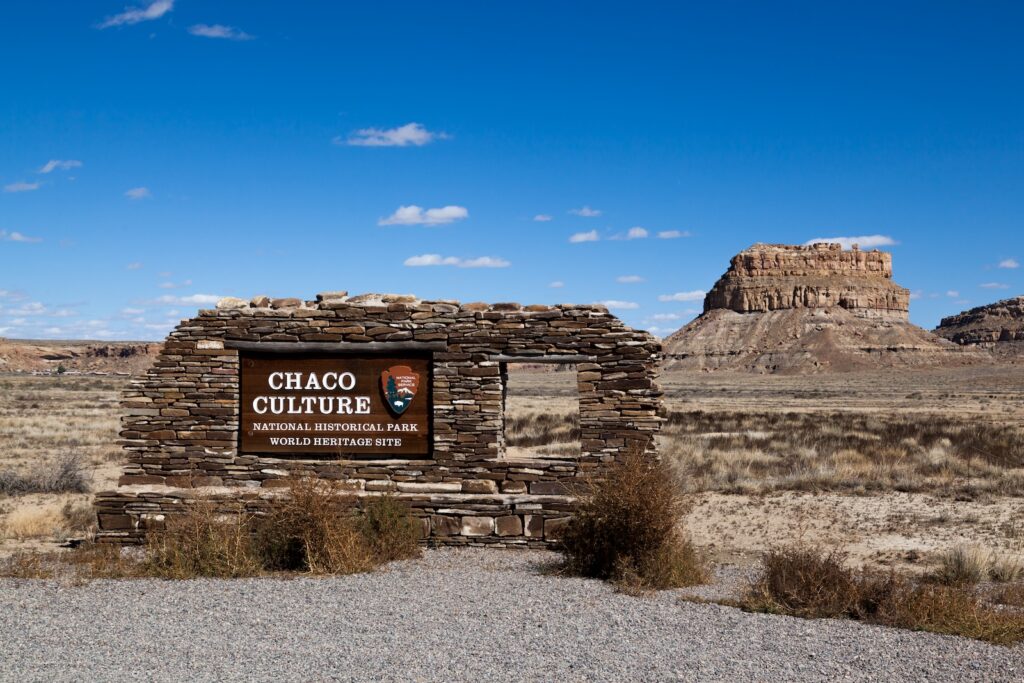 The Chaco Culture National Historical Park sign with ruins in the background